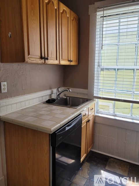 A kitchen with wooden cabinets and a tiled counter.