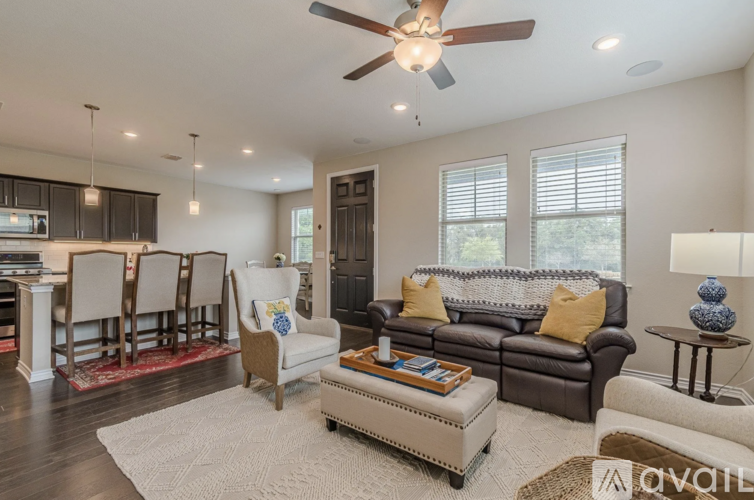 A living room with a brown leather couch and a white chair.
