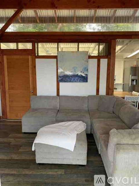 A living room with a grey couch and a painting on the wall.