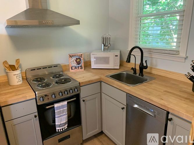 A kitchen with a stove, sink, and microwave.