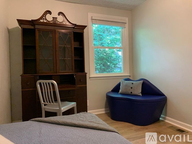 A room with a bed, a chair, a cabinet, and a bean bag chair.