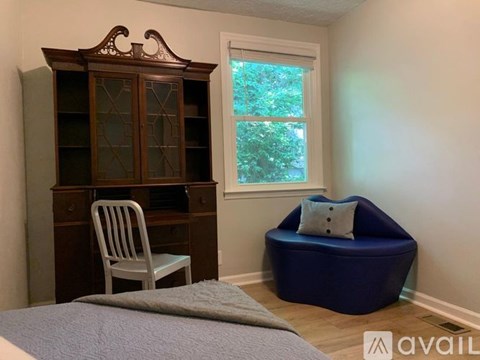 A room with a bed, a chair, a cabinet, and a bean bag chair.