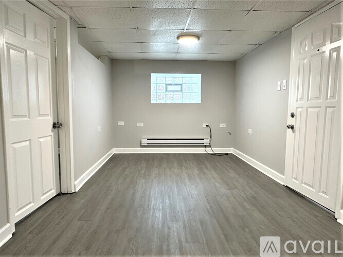 A room with a window, a radiator, and a wooden floor.
