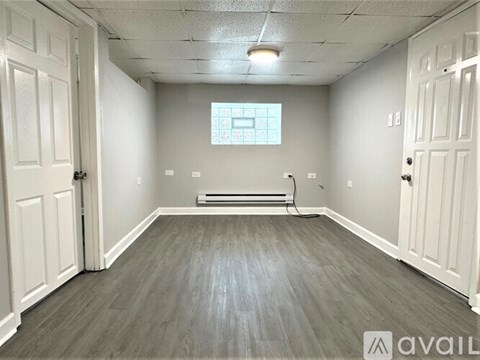 A room with a window, a radiator, and a wooden floor.