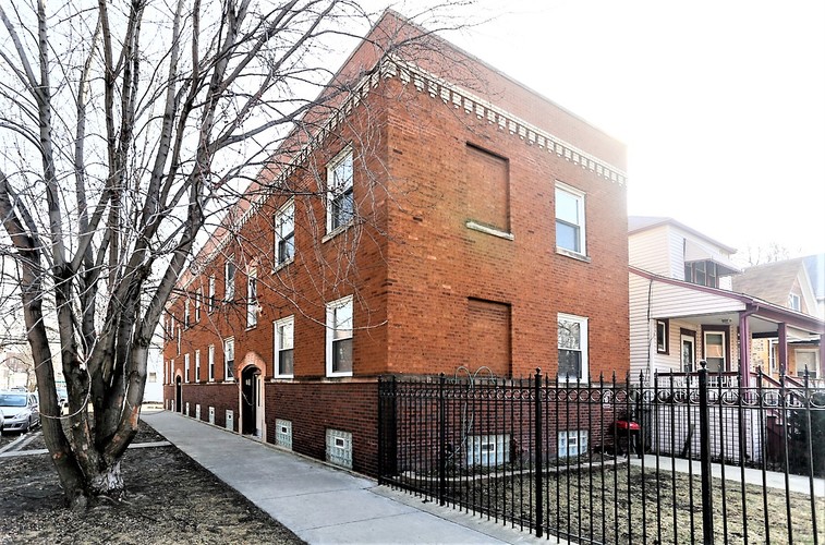 A red brick building with a black fence in front.