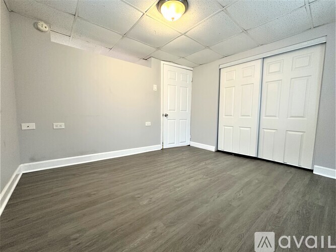 A room with grey walls, wooden flooring, and two white doors.