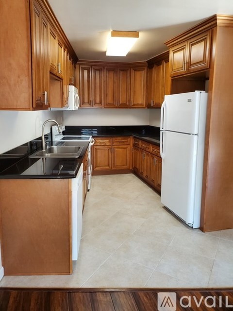 A kitchen with wooden cabinets and a white fridge.