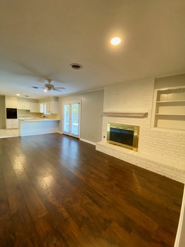 A living room with a fireplace and wood flooring.
