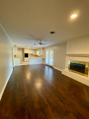 A spacious room with wooden floors and a fireplace.