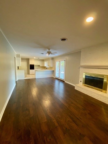 A spacious room with wooden floors and a fireplace.