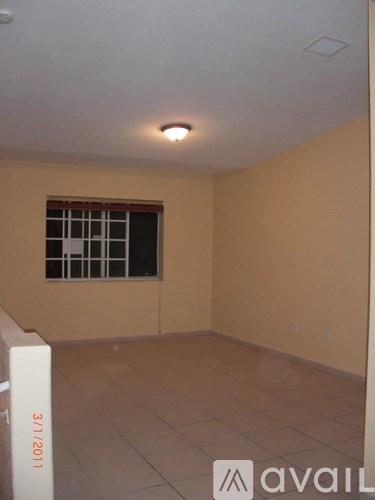 A room with beige walls and a window with bars on it.