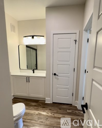A white bathroom with a toilet, sink, and mirror.