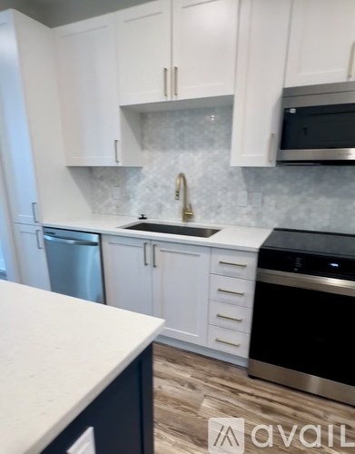 A kitchen with white cabinets and a black island.