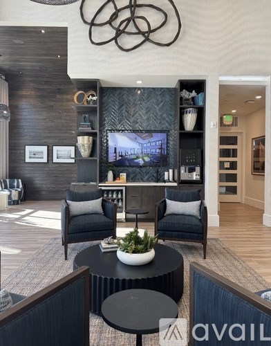 A modern living room with a TV, two chairs, and a coffee table.