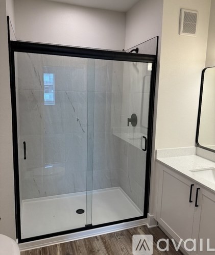 A glass shower enclosure with a black frame is in a white bathroom.