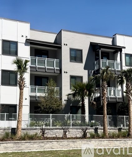 A modern building with balconies and palm trees in front.