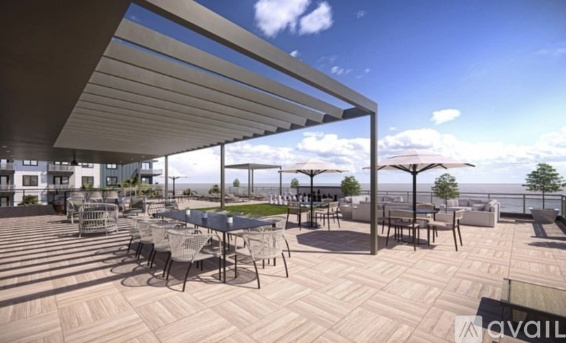 A patio with tables and chairs is covered by a roof.