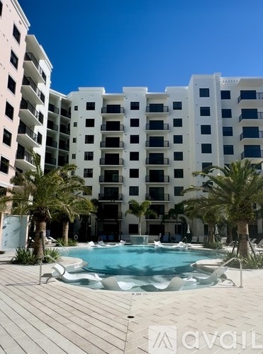 A pool in front of a white building with palm trees.