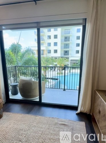 A balcony with a chair and a table overlooking a pool.