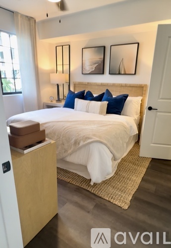 A bedroom with a bed, nightstand, and two pictures on the wall.