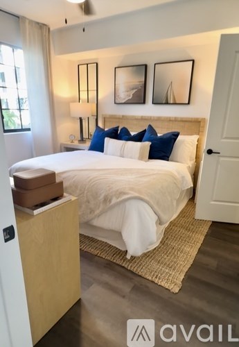 A bedroom with a bed, nightstand, and two pictures on the wall.