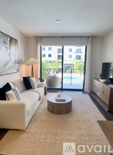 A living room with a white couch and a coffee table in front of a large window.