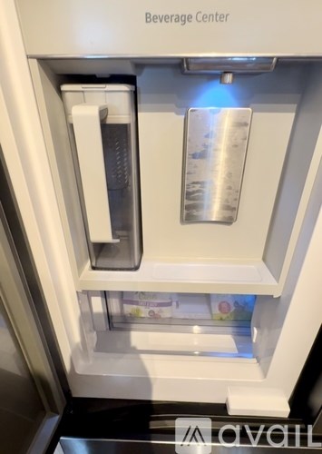 A beverage center with a water dispenser and a glass door.