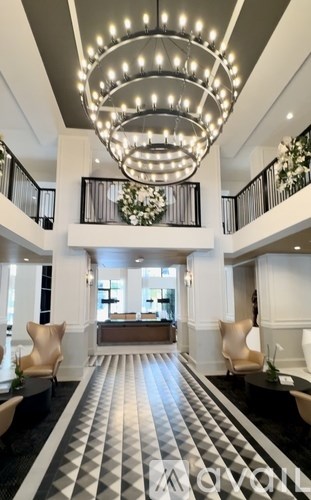A large, elegant chandelier hangs over a spacious, well-decorated foyer.