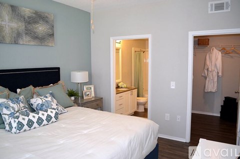A bedroom with a bed, nightstand, and a painting on the wall.