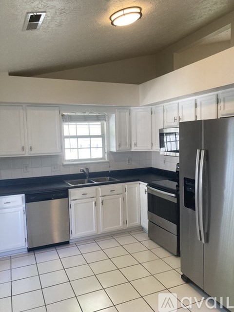 A kitchen with white cabinets and a stainless steel refrigerator.