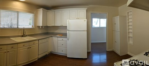 A white refrigerator in a kitchen with white cabinets.