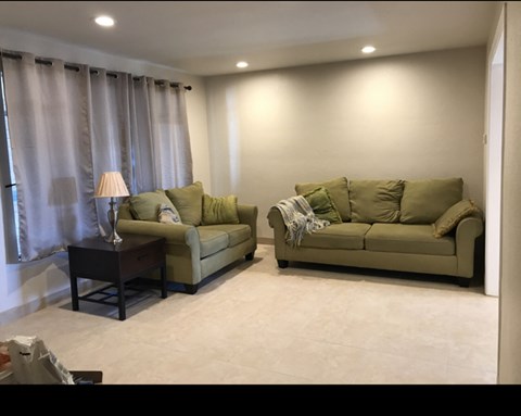 A living room with two couches and a table with a lamp on it.