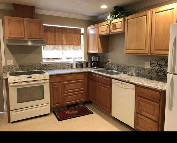 A kitchen with wooden cabinets and a white stove top oven.