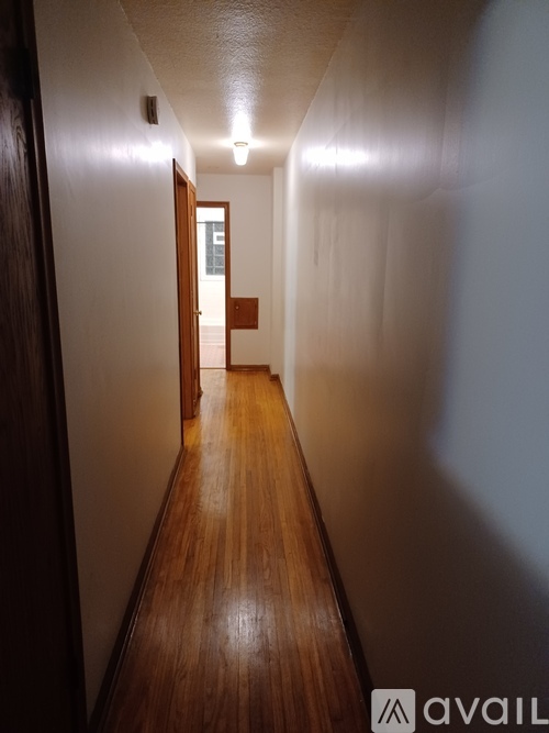 A long hallway with wooden floors and doors on either side.