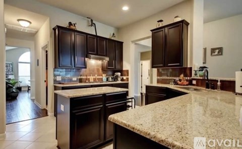A kitchen with dark brown cabinets and a granite countertop.