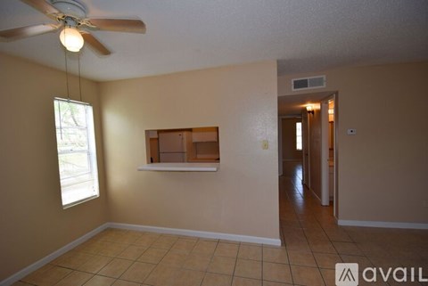 A room with a ceiling fan and a window with a view of trees.
