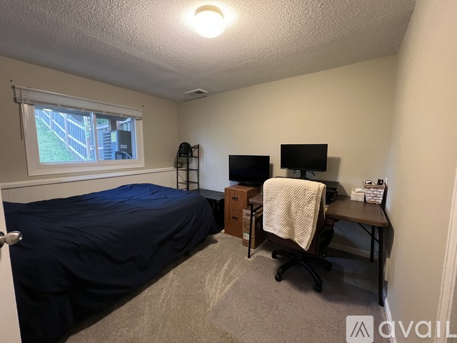 A bedroom with a bed, desk, and window.