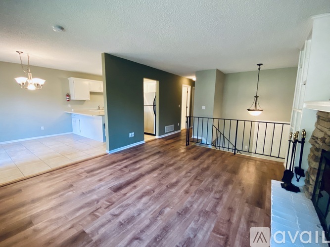 A spacious room with wooden flooring and a balcony with a black railing.