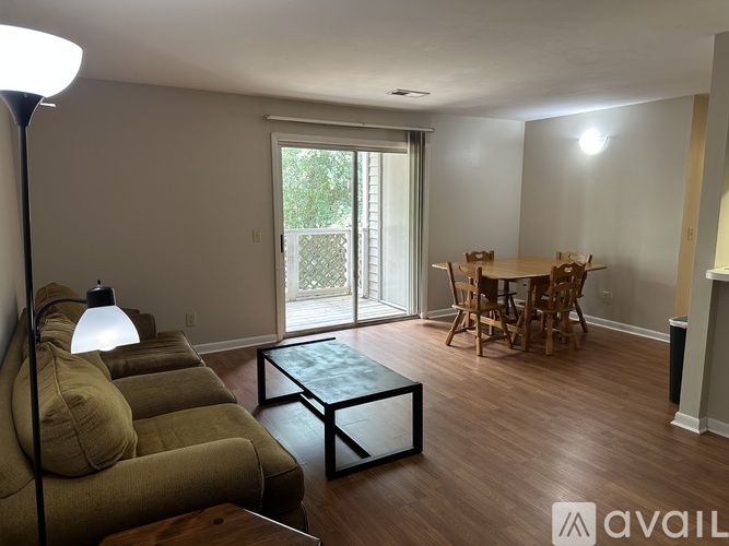 A living room with a white chair, a brown couch, and a black coffee table.