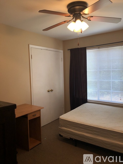 A bedroom with a bed, desk, and window.