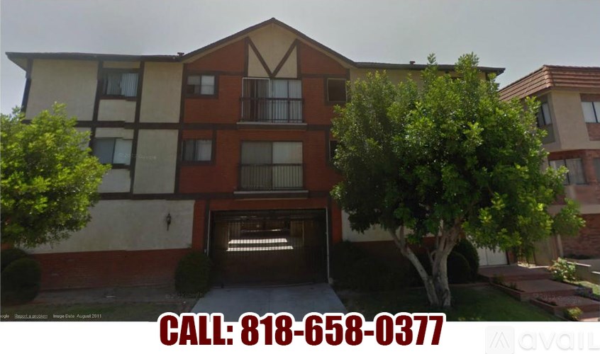 A building with a brown and beige facade has a tree in front of it.
