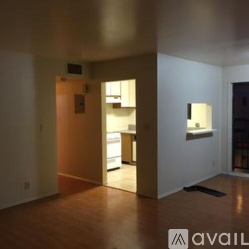 A room with a lamp on the wall and a doorway leading to another room.