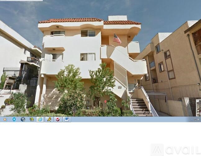 A modern white building with a balcony and a flag on the top.