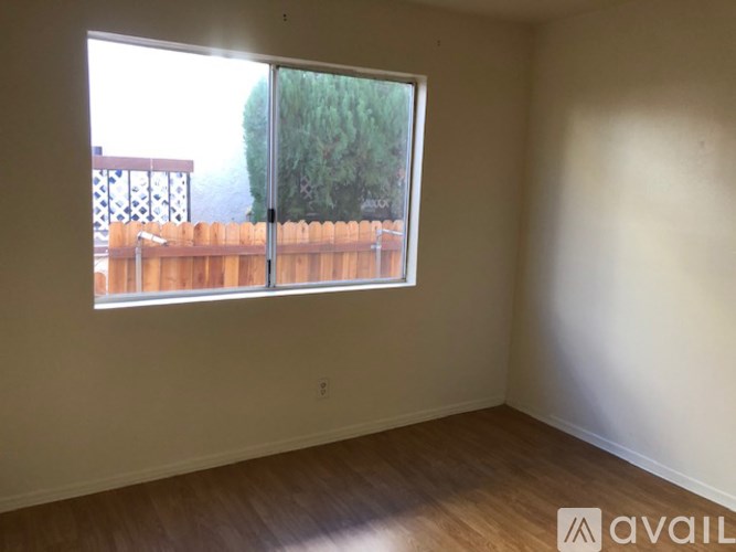 A room with a window overlooking a wooden fence and trees.