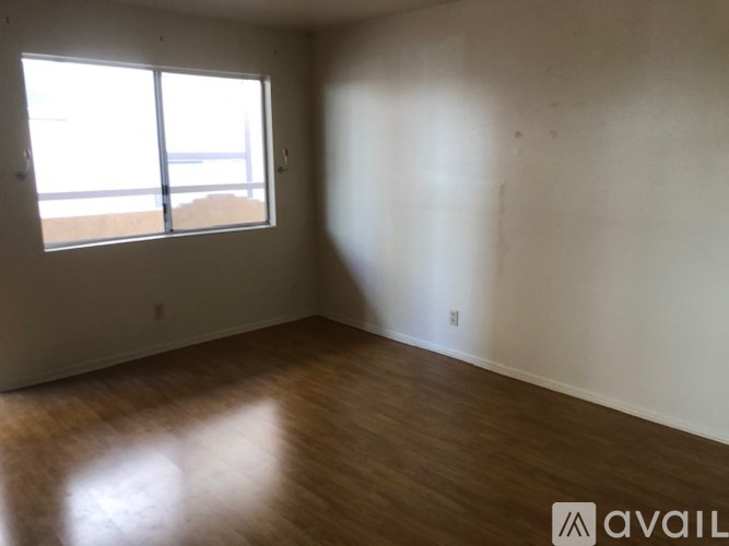 Empty room with wooden floor and large window.