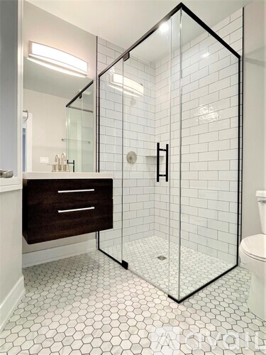 A white tiled bathroom with a walk in shower.