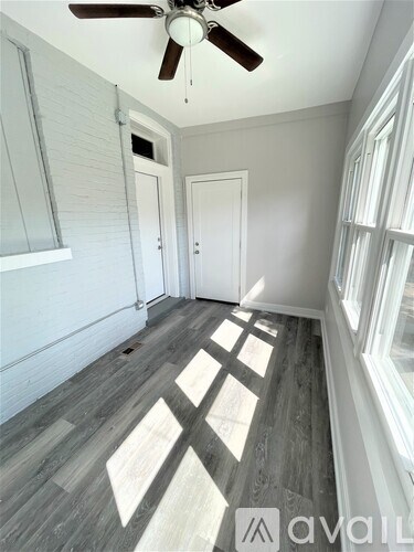A room with a ceiling fan and wooden flooring.