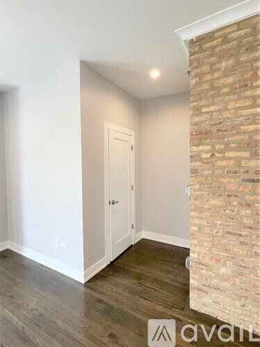 A room with a white door and a brick wall.