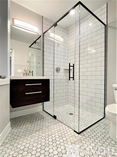 A white tiled bathroom with a walk-in shower.