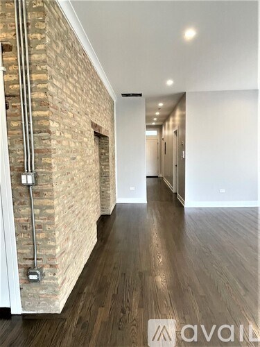 A hallway with a brick wall on the left and wooden flooring.